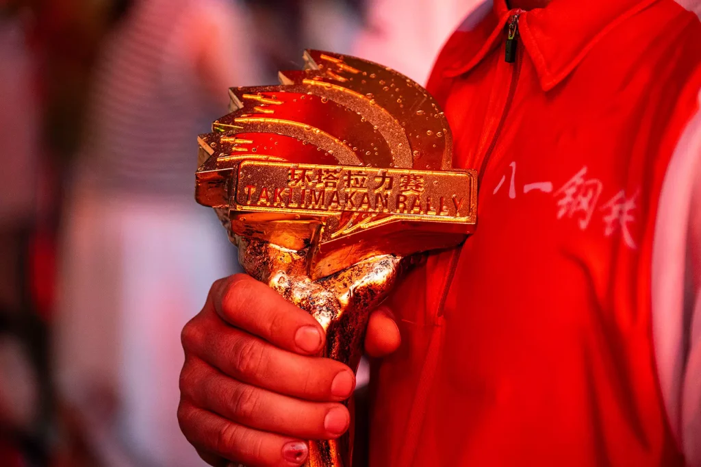 KOVE team holding Taklimakan Rally golden trophy